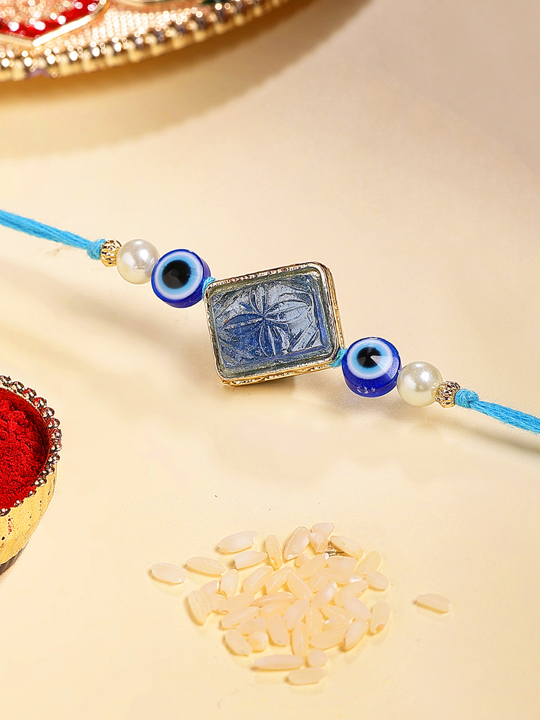 Karatcart Gold Plated Blue Carved Stone Evil Eye Kundan Bhiya Rakhi with Roli & Chawal