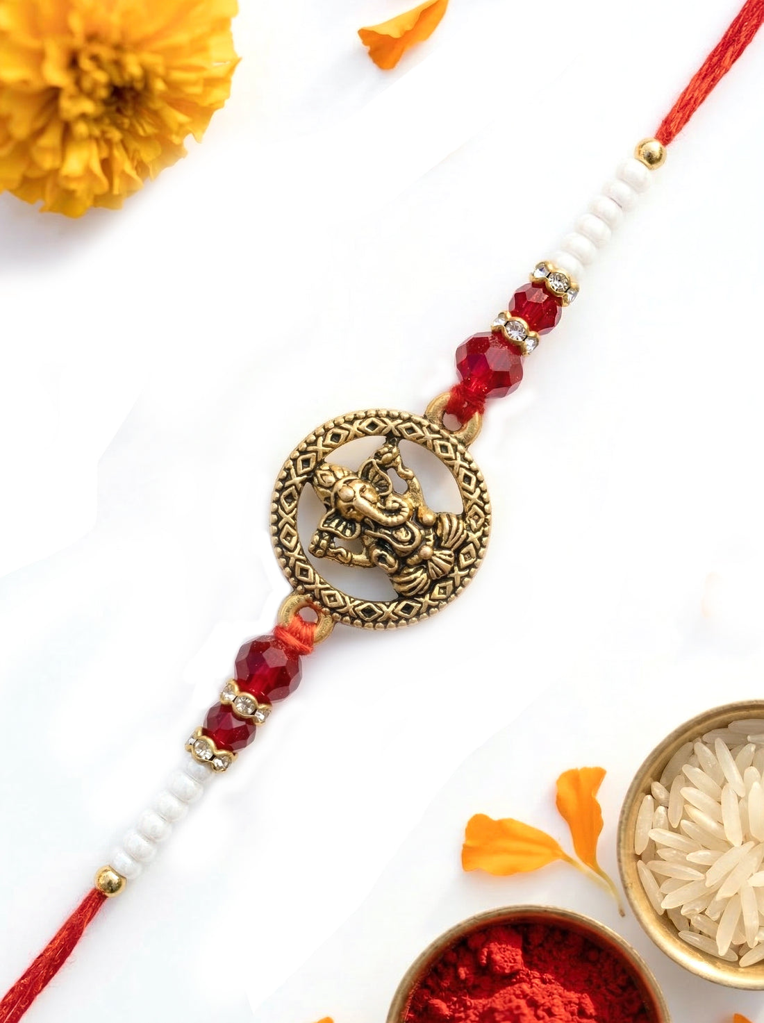 KARATCART Gold Plated Red Crystal Ganesha Bhaiya Rakhi with Roli & Chawal