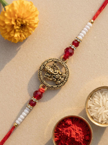 KARATCART Gold Plated Red Crystal Ganesha Bhaiya Rakhi with Roli & Chawal