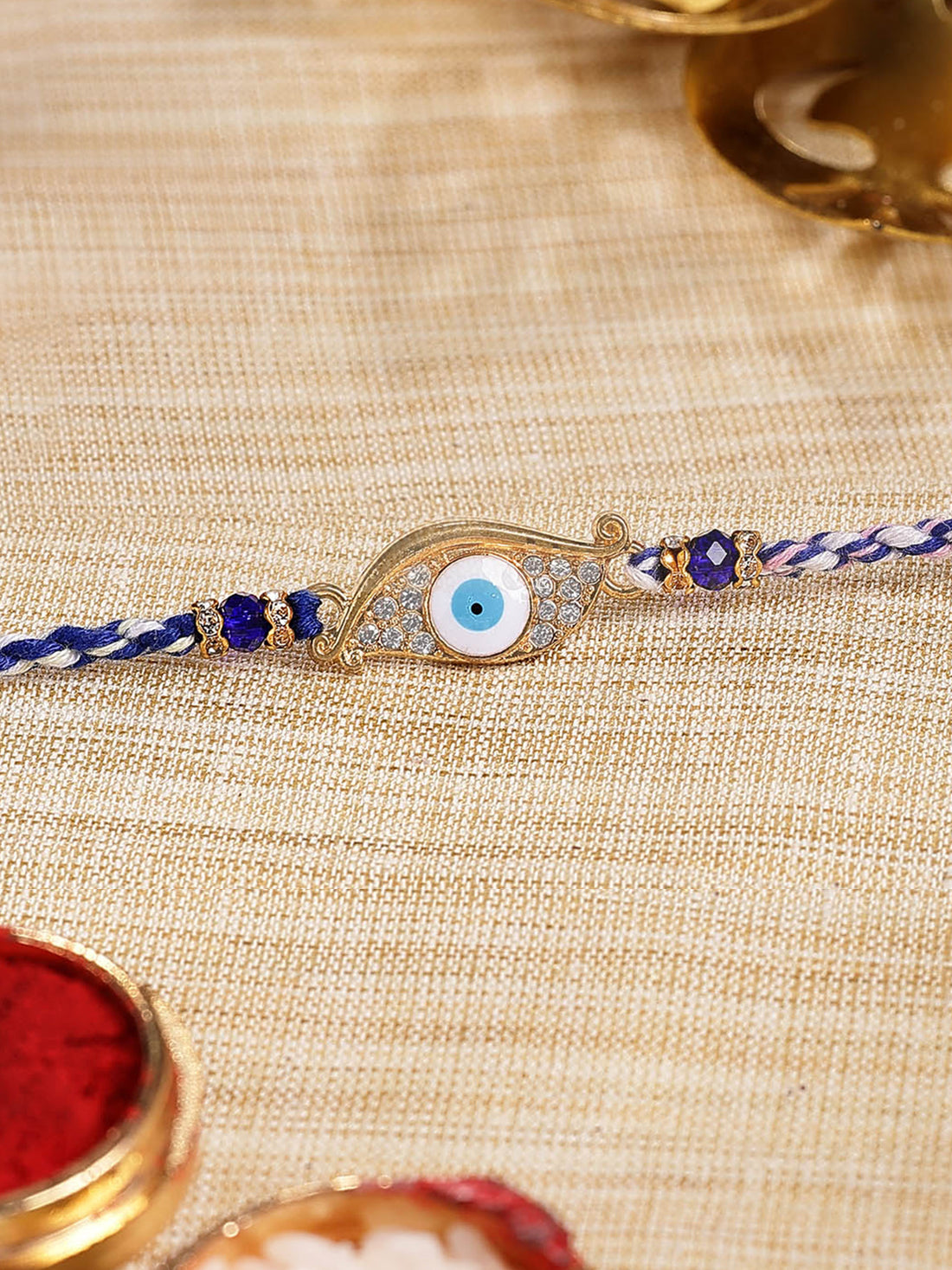 Karatcart Gold Plated Blue American Diamond Eye Shape Evil Eye Bhiya Rakhi with Roli & Chawal